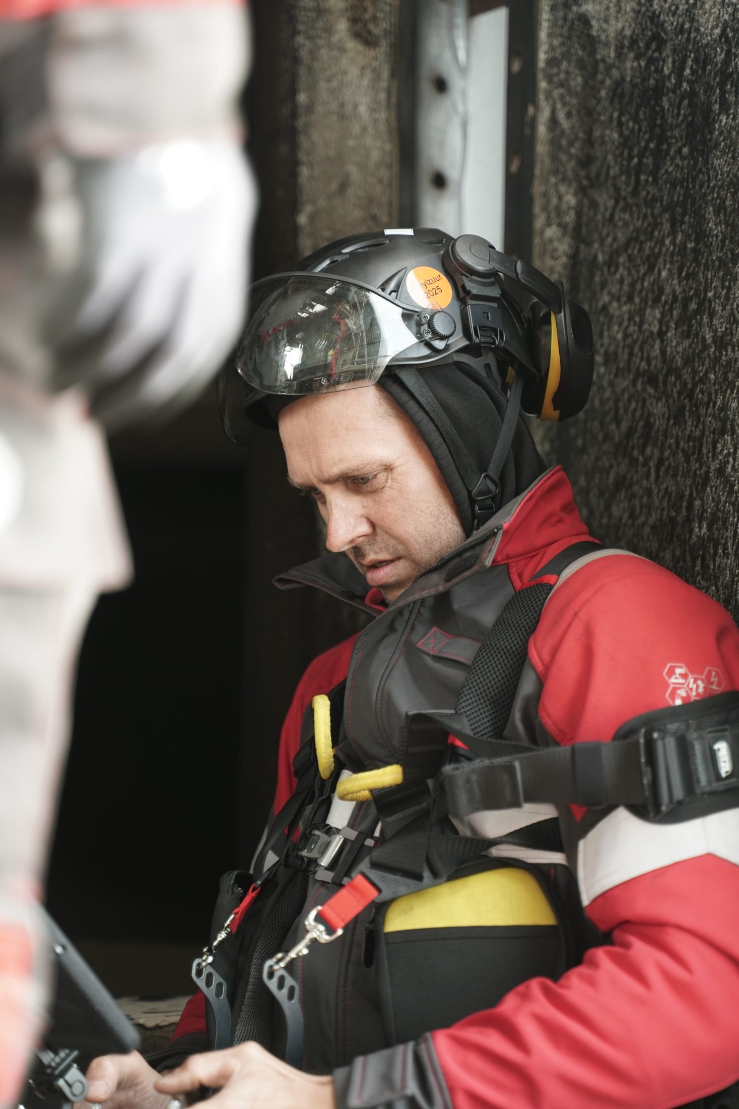 Pilot in visored helmet and harness at a dark tank entry